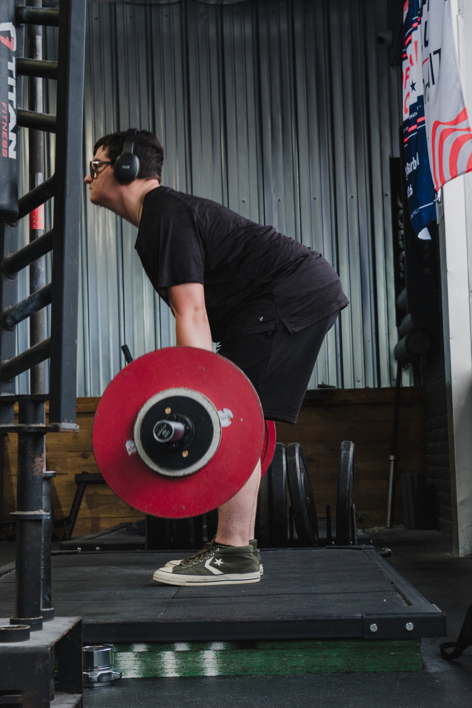 A lifter chalks up and sets his grip before a deadlift on the competition platform, a USA Powerlifting banner behind him.
