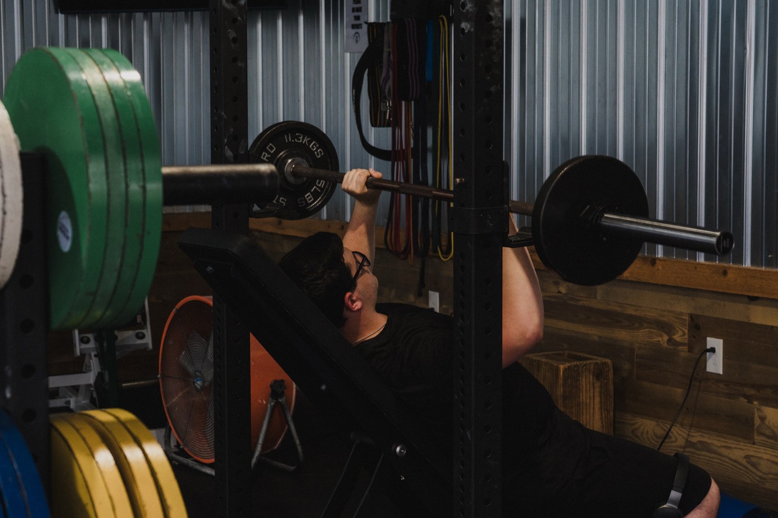 A member presses a loaded barbell on an incline bench inside the main gym.